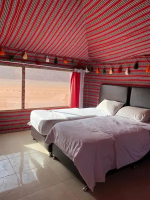 a bedroom with two beds and a red wall at Crescent Camp & Tours in Wadi Rum