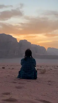a person sitting in the desert watching the sunset at Crescent Camp & Tours in Wadi Rum