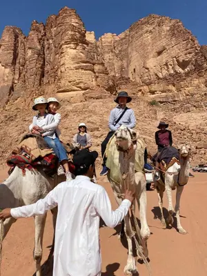 a group of people riding on camels in the desert at Crescent Camp & Tours in Wadi Rum