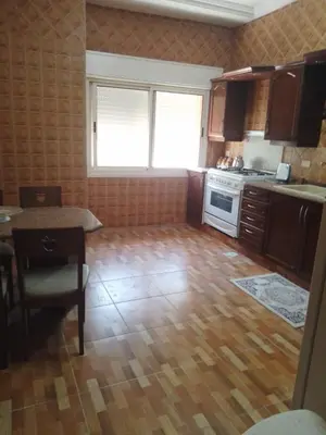 a small kitchen with a wooden floor and a table at Furnished apartment for rent in Amman