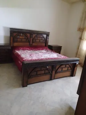 a bedroom with a wooden bed with a red mattress at Furnished apartment for rent in Amman