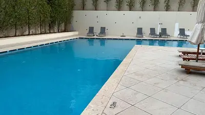 a large swimming pool with chairs and blue water at Flow - Al Raha Village in Aqaba