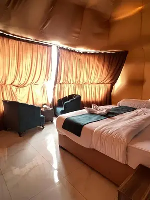 a bedroom with a bed and a chair in a room at RUM PILLARS REST houstl in Wadi Rum
