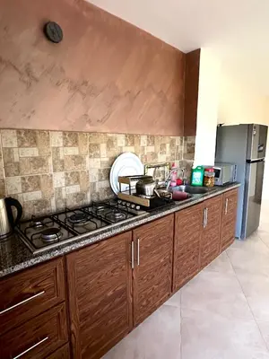 a kitchen with wooden cabinets and a stove top oven at sama vailla in Amman
