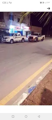 two trucks parked on a city street at night at فيلا فاخره على مساحة أرض كبيرة وهادئة in Şabḩā