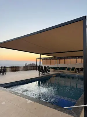 a canopy over a swimming pool next to a pier at شاليه ومزرعة طبقة فحل Chalet Pella