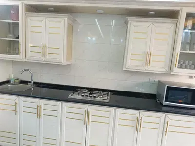 a kitchen with white cabinets and a sink and a microwave at شاليه ومزرعة طبقة فحل Chalet Pella