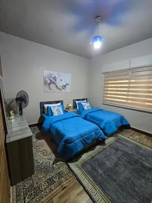 two beds in a room with blue pillows at Deluxe Furnished Studio Jubaiha in Amman