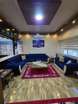 a living room with a blue couch and a table at Deluxe Furnished Studio Jubaiha in Amman