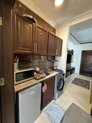 a kitchen with wooden cabinets and a washer and dryer at MK5 - One bedroom Apartment in Amman