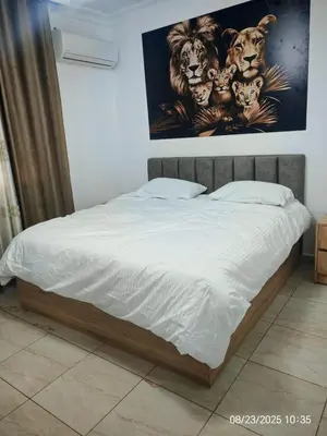 a bed in a bedroom with a painting on the wall at EVANNA SUITE & HOTELs VIP ايفانا للشقق الفندقيه VIP in Amman
