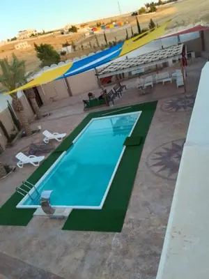 a swimming pool with umbrellas and tables and chairs at شاليه هاف مليون الرامة in Al Mazār
