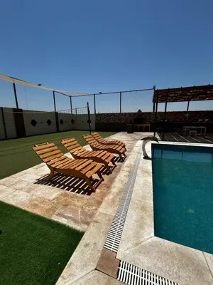 a group of lounge chairs next to a swimming pool at شاليه هاف مليون الرامة in Al Mazār