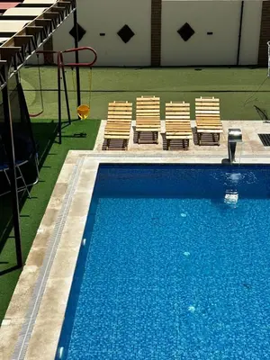 a swimming pool with two chairs and a swing at شاليه هاف مليون الرامة in Al Mazār