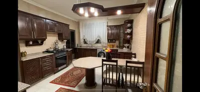 a kitchen with wooden cabinets and a table with chairs at Comfort Apartment in Amman