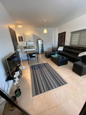 a living room with a black couch and a kitchen at Studio for Rent in Jabal Alweibdeh-Amman - Jordan in Amman