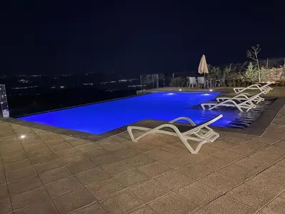 a swimming pool at night with two lounge chairs at sofia Farm in Al Salt