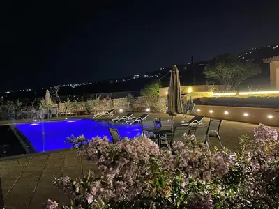 a swimming pool at night with chairs and umbrellas at sofia Farm in Al Salt