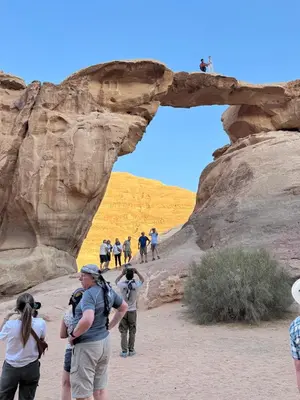 a group of people taking pictures of a rock formation at cave under the stars in Wadi Rum