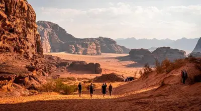 a group of people walking down a dirt road in the desert at cave under the stars in Wadi Rum