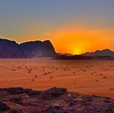 a sunset in the desert with mountains in the background at مخيم علاء in Wadi Rum
