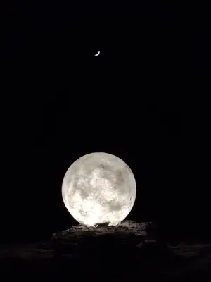 a moon in the night sky with a small moonresent at مخيم علاء in Wadi Rum