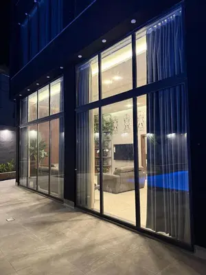 a building with large glass doors with a couch inside at Taj Villa 2 - entire Villa in Deadsea front beach in Sowayma