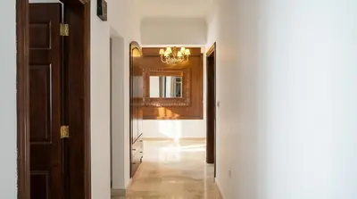 a hallway with white walls and a chandelier at Cozy & Spacious 3 En-Suite Bedroom Apartment in Amman