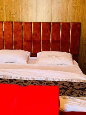 a bed with a wooden headboard and a red blanket at Desert yanal wadi rum in Disah