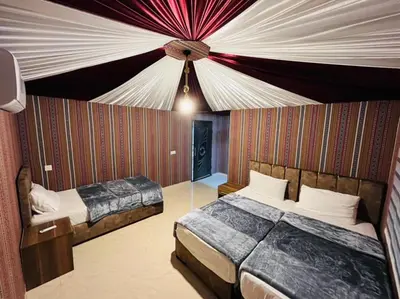 a bedroom with two beds and a ceiling at Desert yanal wadi rum in Disah