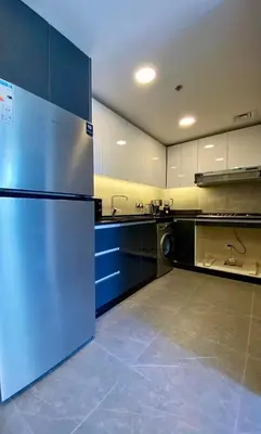 a large kitchen with a refrigerator and a sink at Sunny Duplex for rent in Abdali in Amman