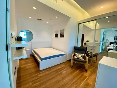 a bedroom with a bed and a chair and a mirror at Sunny Duplex for rent in Abdali in Amman