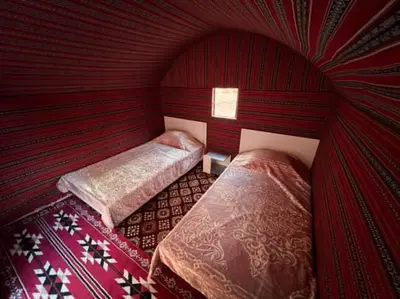 two beds in a room with red walls at Mountain Stars Camp in Wadi Rum