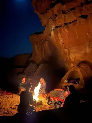 a group of people sitting around a fire in a cave at Mountain Stars Camp in Wadi Rum
