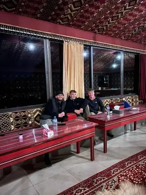 a group of three men sitting at tables in a room at Mountain Stars Camp in Wadi Rum