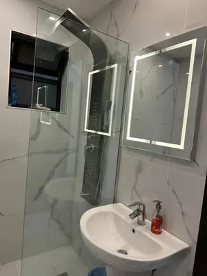 a bathroom with a sink and a shower with a mirror at 3 Bedrooms Flat in Rabwat Abdoun in Amman