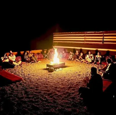 a group of people are sitting around a fire at Nayef camp wadi Rum in Wadi Rum