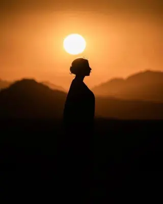 a person standing in front of a sunset at Wadi Rum Bubbles Luxury Camp in Wadi Rum