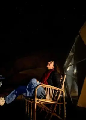 a woman sitting in a chair at night at Wadi Rum Bubbles Luxury Camp in Wadi Rum