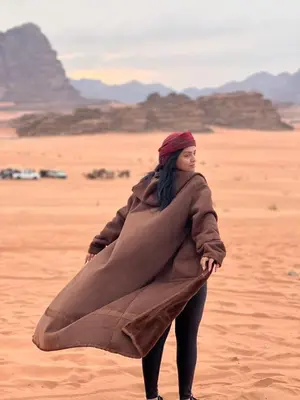 a woman standing in the desert holding a blanket at Isabella Luxury Wadi Rum in Wadi Rum