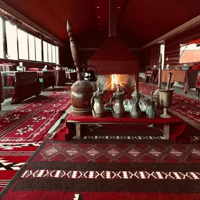a living room with a fireplace in a room with red carpet at Super Delxue Tent in Azraq ash Shīshān