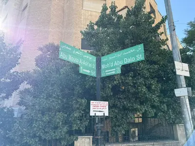 two green street signs on a pole in front of a building at 2BR Apartment in Tlaa Al Ali, Parking, AC, WIFI in Amman