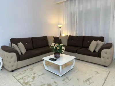 a living room with a couch and a table with flowers at Two-Bedroom Apartment in Swefieh in Amman