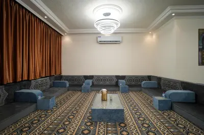 a waiting room with a table and blue chairs at الوجيه للشقق الفندقية in Amman