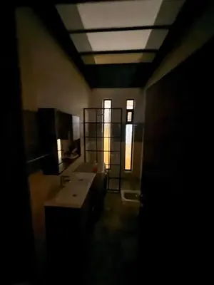a dark bathroom with a sink and a window at Private Chalet in Dabouq , Night-Lit in Amman