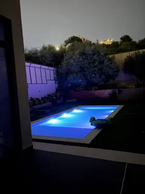 a swimming pool with blue lights in a backyard at night at Private Chalet in Dabouq , Night-Lit in Amman