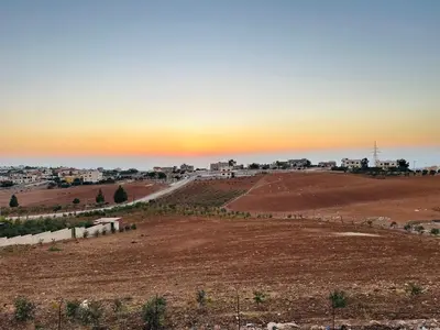 an empty field with the sunset in the background at شقة مفروشة واسعة وهادئة in Umm Juraysāt