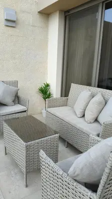 a patio with wicker furniture and a table and chairs at Al-Raha Luxury apartment in Aqaba