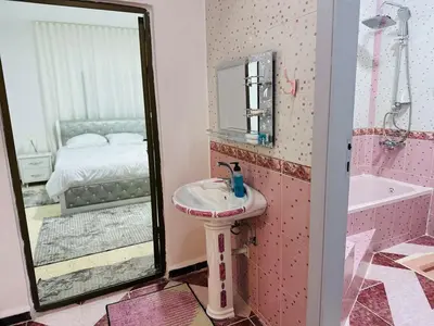 a bathroom with a sink and a mirror and a bed at شقة واسعة وهادئة in Umm Juraysāt