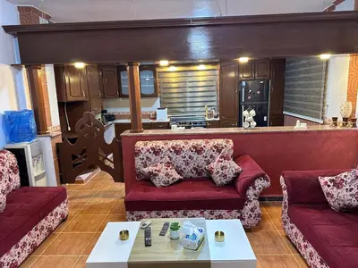 a living room with two red couches and a kitchen at شقة واسعة وهادئة in Umm Juraysāt